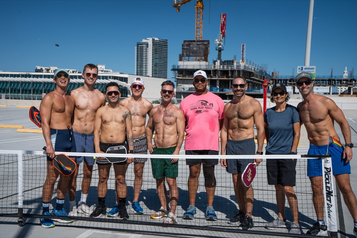 The whole queer pickleball group lined up at the net for a photo with the Miami skyline behind