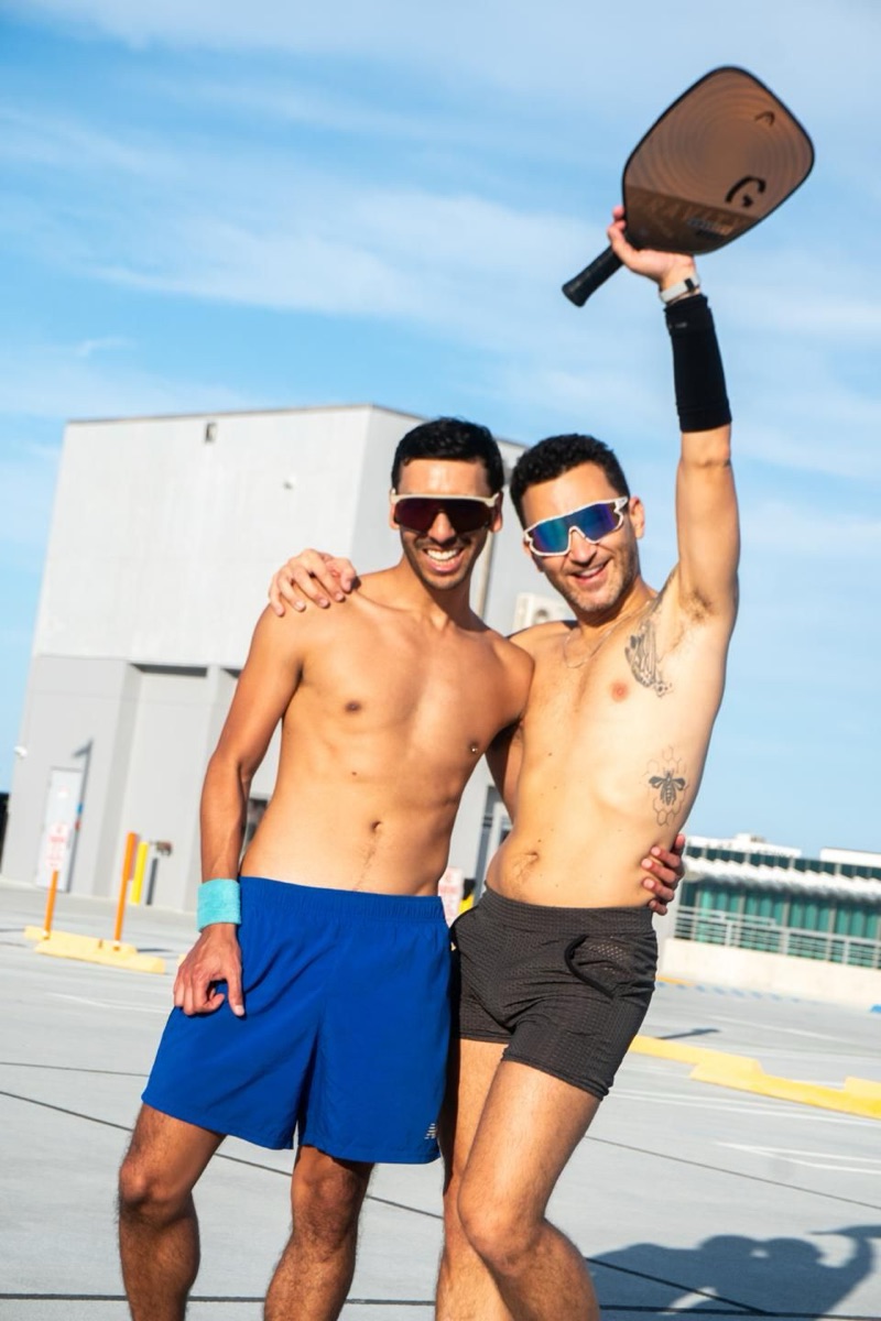 Two friends from our queer pickleball community celebrating with a raised paddle after a win